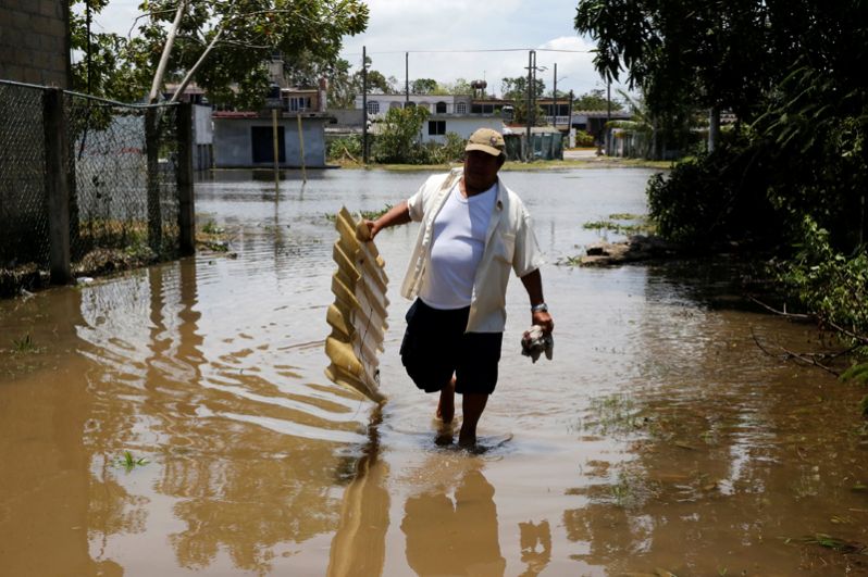 Человек переходит затопленную улицу после урагана ураган «Франклин» в городе Наутла.