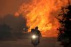 Местные жители на мотоцикле спасаются от лесных пожаров возле деревни Варнавас.