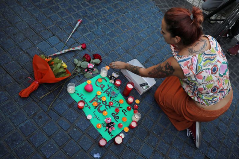 Цветы и свечи на улице Рамбла в Барселоне. Надпись на плакате: «Каталония — место мира».