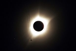 Самолет пролетает на фоне солнечного затмения. Гернси, штат Вайоминг.