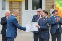Алексей Гордеев вручил директору школы Роману Ткачёву подарок - сертификаты на получение школьного автобуса и приобретение учебного оборудования.