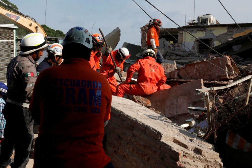 Спасатели ищут тела под обломками зданий после землетрясения.