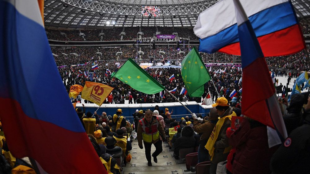 Зрители на митинге-концерте «Россия объединяет!» на большой спортивной арене «Лужники» в Москве.