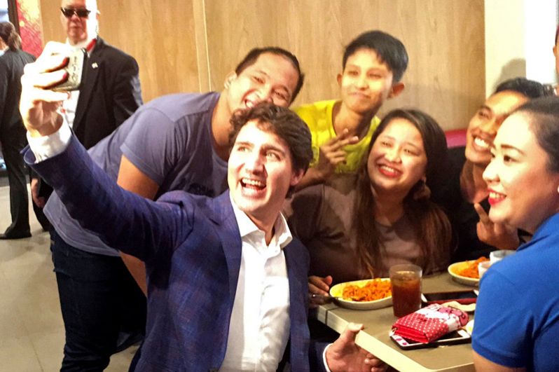 Премьер-министр Канады Джастин Трюдо делает селфи с местными жителями во время своего визита в ресторан быстрого питания Jolibee в Тондо, Манила.