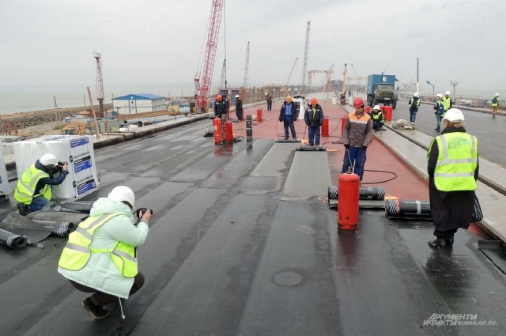 Журналисты фотографируют процесс гидроизоляции мостового полотна. 