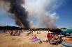 Туристы отдыхают на пляже курорта Борм-ле-Мимоза, в то время как в регионе бушуют лесные пожары, Франция. 26 июля 2017 года. 