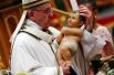 Папа Римский Франциск держит статуэтку младенца Иисуса во время традиционной полуночной мессы в базилике Святого Петра в канун Рождества в Ватикане. 