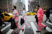 Мужчины в праздничных костюмах идут по 6-й авеню в Нью-Йорке в канун Рождества.