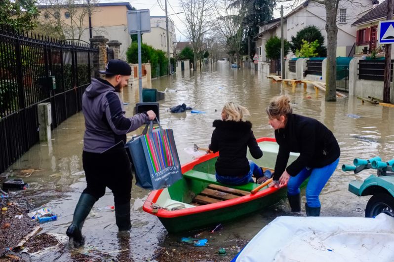 Местные жители переправляются на лодке на одной из затопленной улице в Париже после прошедших ливневых дождей.