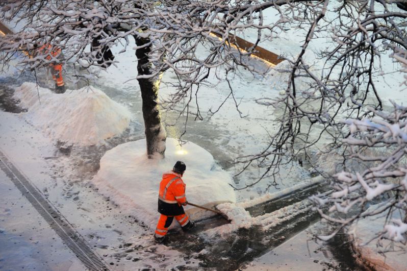Сотрудники коммунальных служб убирают снег на улице в Москве.