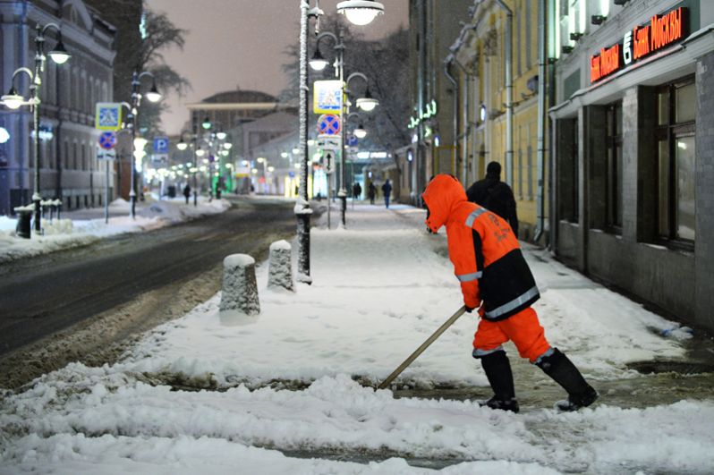Сотрудник коммунальной службы убирает снег на улице в Москве.