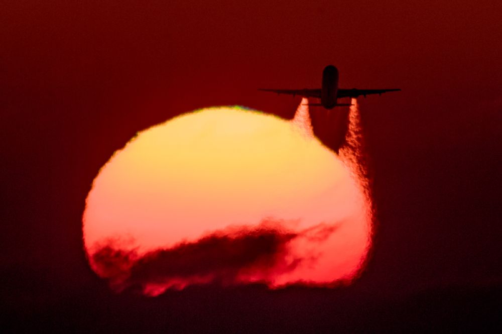 Летящий самолет Airbus A-321 на фоне заката.