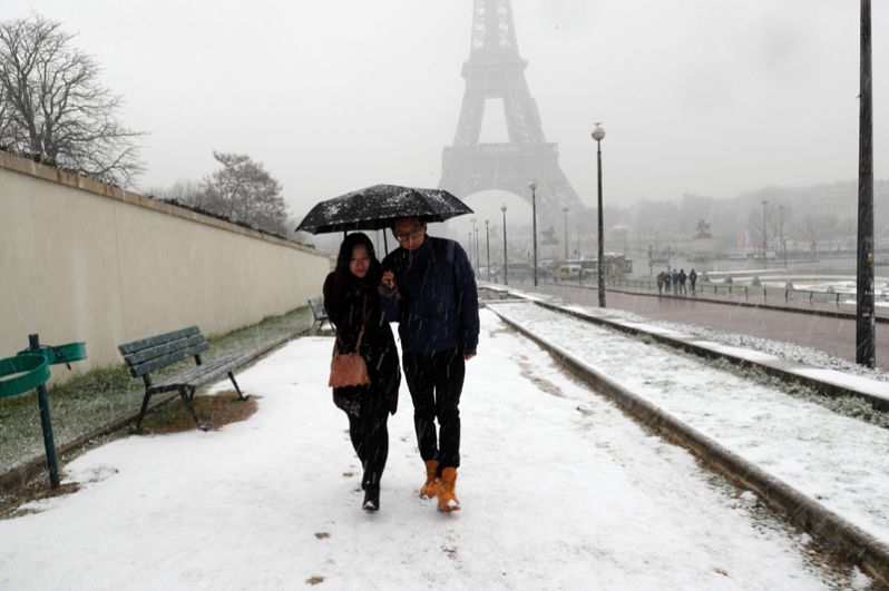 Прохожие во время снегопада в Париже, Франция.