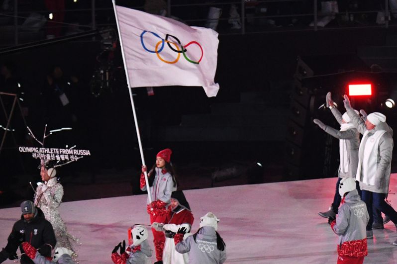 Волонтер несет олимпийский флаг, сборная России приветствуют зрителей на церемонии открытия XXIII зимних Олимпийских игр в Пхенчхане.