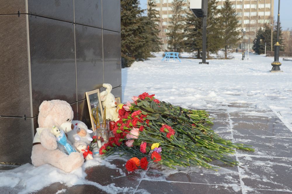 Цветы, свечи и детские игрушки у памятника Ленину в центре Орска.