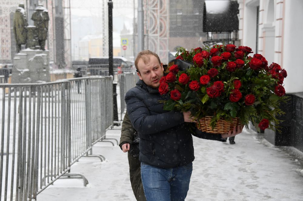 Мужчина несет цветы ко входу в здание МХТ имени Чехова в Камергерском переулке.