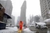 Рабочий убирает снег перед Флэтайрон-билдинг в Нью-Йорке.