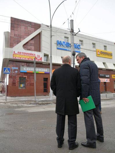 Президент осматривает фасад сгоревшего здания. Его сопровождает полпред президента РФ в Сибирском федеральном округе Сергей Меняйло.