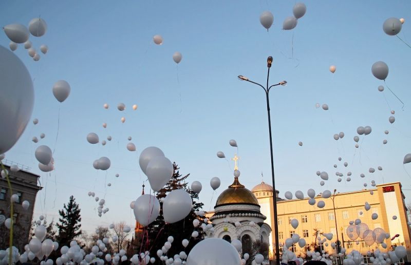 В Иркутске в небо запустили десятки белых шариков в память о погибших детях.