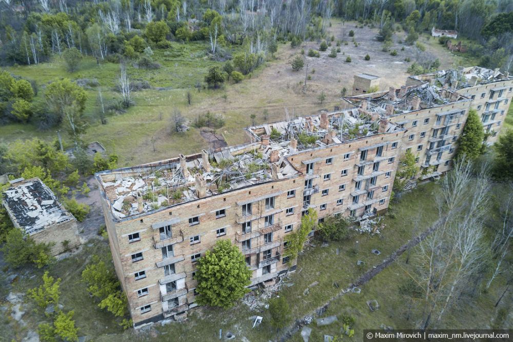 Город Полесское уже на камере с дрона выглядит удручающе - на крышах домов растут березки, все дворы и улицы стали непроходимым лесом. Городок затерян в лесах Черниговщины и разделен на две части рекой Уж. Именно поэтому Полесское был в числе первых городов, эвакуированных из зоны ЧАЭС. Сейчас там нет ни отопления, ни газа, ни электричества и постоянно живет 10 человек.