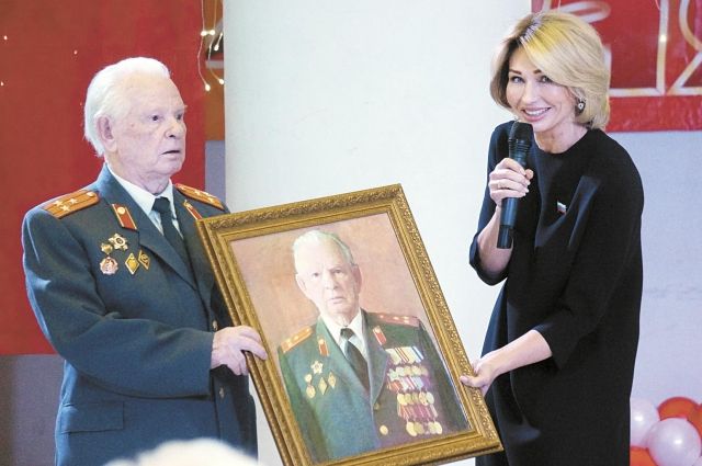 Татьяна Шестакова вручает участнику войны Аркадию Бронникову  его портрет.