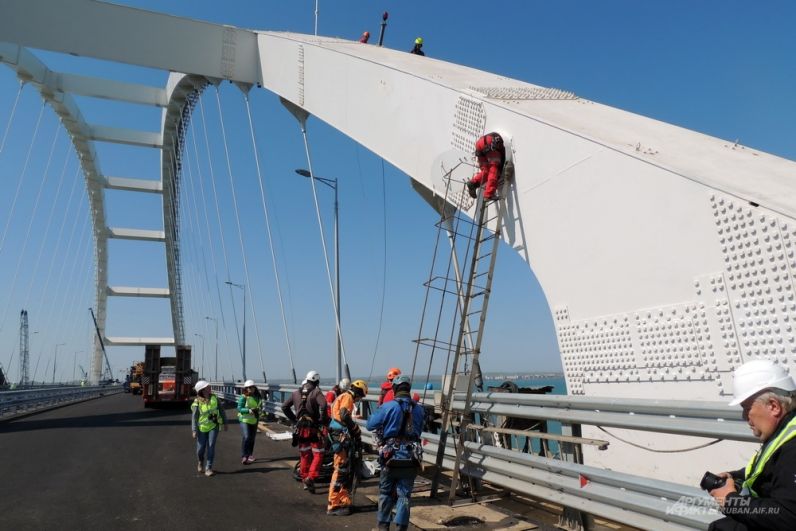 Промышленные альпинисты поднимаются на автомобильную арку моста для монтажа архитектурной подсветки.