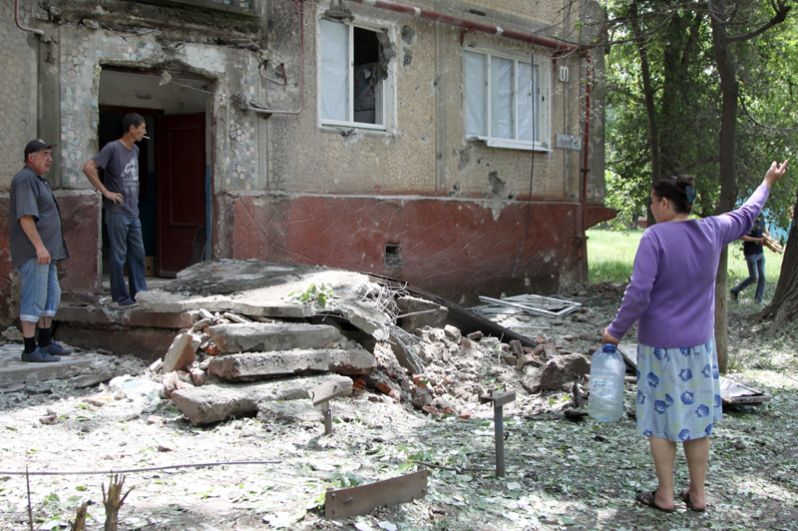 Жители во дворе жилого дома, пострадавшего в результате обстрела, в поселке Горловка Донецкой области.