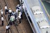 Пассажиры сходят с поезда, движение которого была приостановлено после землетрясения в Такацуки.
