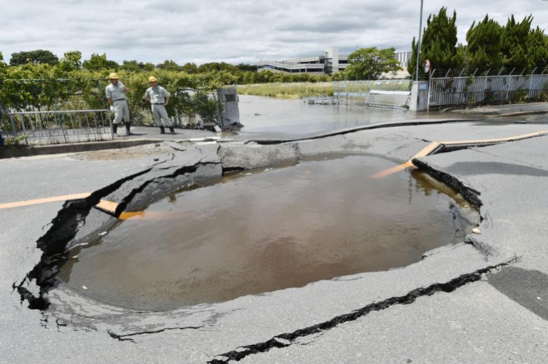 Трещины на дороге после землетрясения, заполненные водой, так как были повреждены водопроводные трубы, Такацуки.