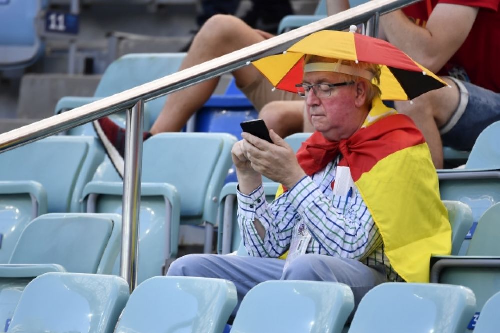 Практичный пожилой болельщик из Бельгии с зонтиком на головном уборе.