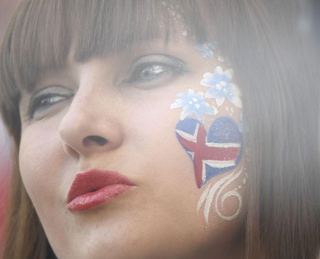 Болельщица исландской сборной с сердцем на щеке расцветки ее национального флага.