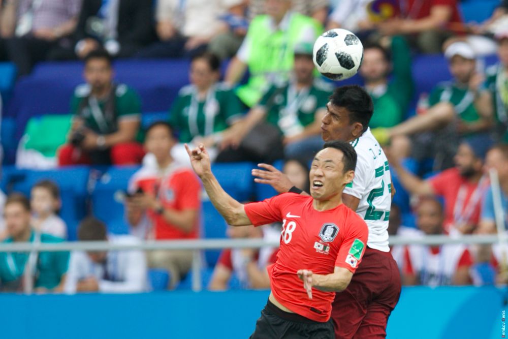 Полузащитник Сон Мин Мун отбивает мяч головой.