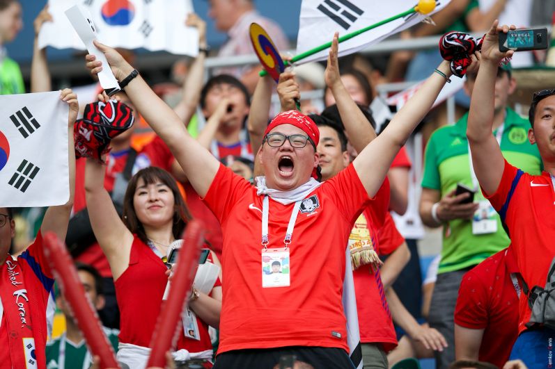 Группа южнокорейских фанатов на трибунах.