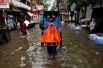 Рикша перевозит пассажиров по улице после сильного дождя в Калькутте, Индия.
