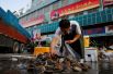 Торговец выбирает моллюски в секции морепродуктов на рыбном рынке в Пекине, Китай.