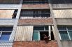 Мужчины заколачивают окна в жилом здании в рамках подготовки к приближающемуся тайфуну в Вэньчжоу.