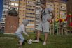 Дети и взрослые во дворах играют в футбол.