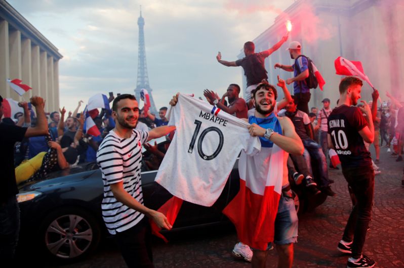 Французы празднуют победу национальной сборной возле Эйфелевой башни в Париже.