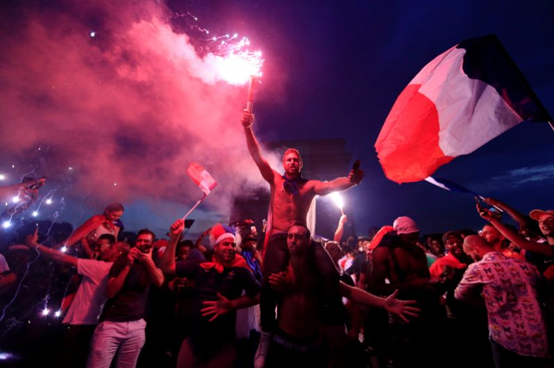 Французы празднуют победу национальной сборной перед Триумфальной аркой на Елисейских полях в Париже.