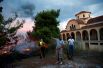 Местные жители принимают участие в тушении пожара рядом с церковью в городе Рафина недалеко от Афин.