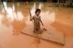 Девочка использует матрас в качестве плота после наводнения, вызванного обрушением дамбы в провинции Аттапу, Лаос.