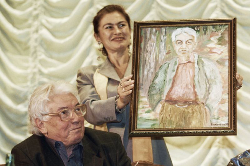 Писатель Владимир Войнович на презентации своей книги. Женщина держит автопортрет писателя.