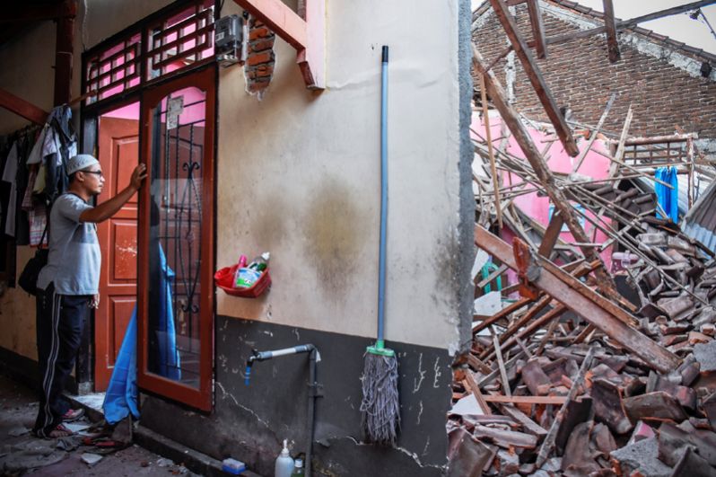 Мужчина около своего дома, разрушенного в результате сильного землетрясения в Ленданге.