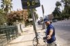 Мужчина фотографируется у электронного табло, которое показывает температуру +50 градусов по Цельсию на улицах Севильи, Испания. 