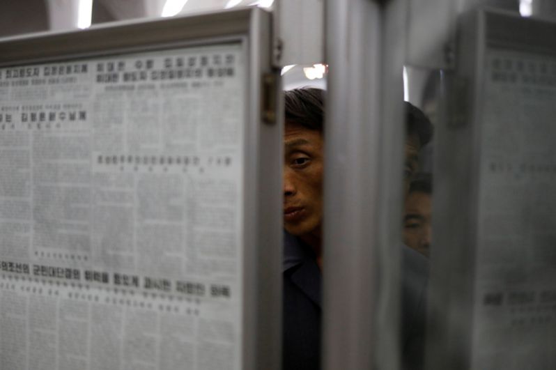 Пассажиры читают газеты на станции метро в Пхеньяне.