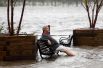 Мужчина на скамейке в затопленном парке в Уилмингтоне, Северная Каролина.