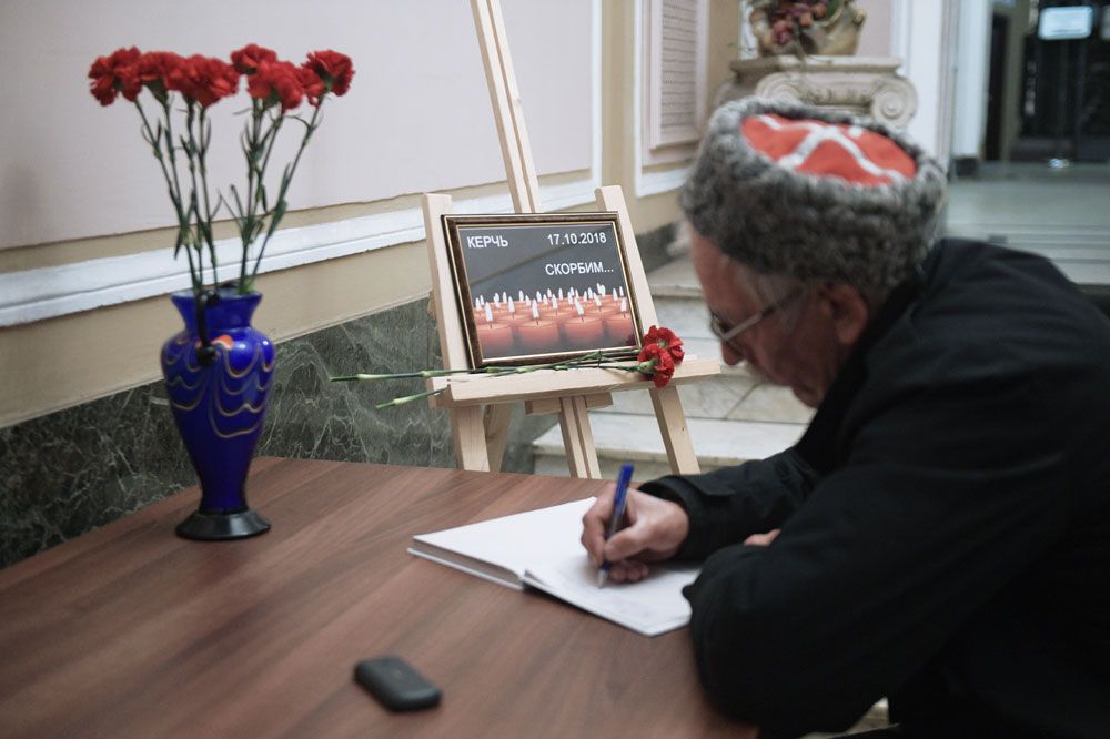 Мужчина оставляет запись в книге соболезнований в Санкт-Петербургском Доме национальностей в связи с происшествием в Керченском политехническом колледже.