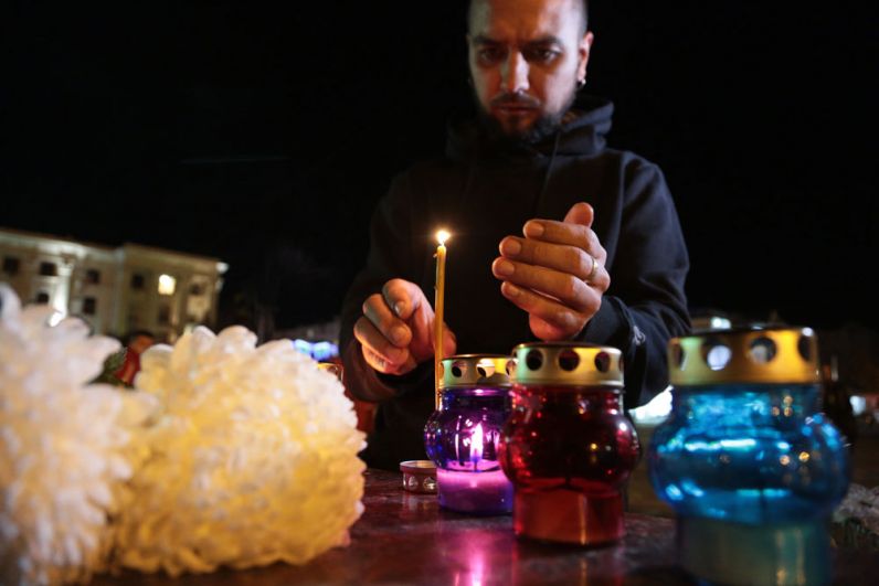 Мужчина зажигает свечу у народного мемориала в Симферополе в память о погибших при нападении на керченский колледж.