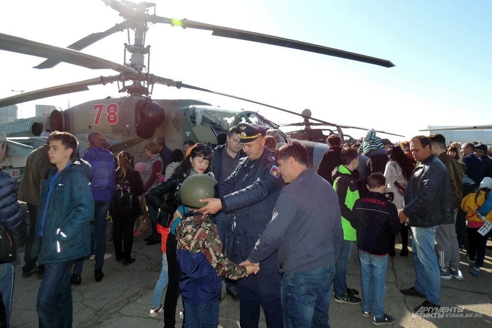 Пилот вертолета дает мальчику примирить свой шлем.
