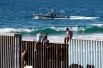Мексиканские мигранты, пытающихся добраться до США, на вершине пограничной стены между Мексикой и Соединенными Штатами, Тихуана.